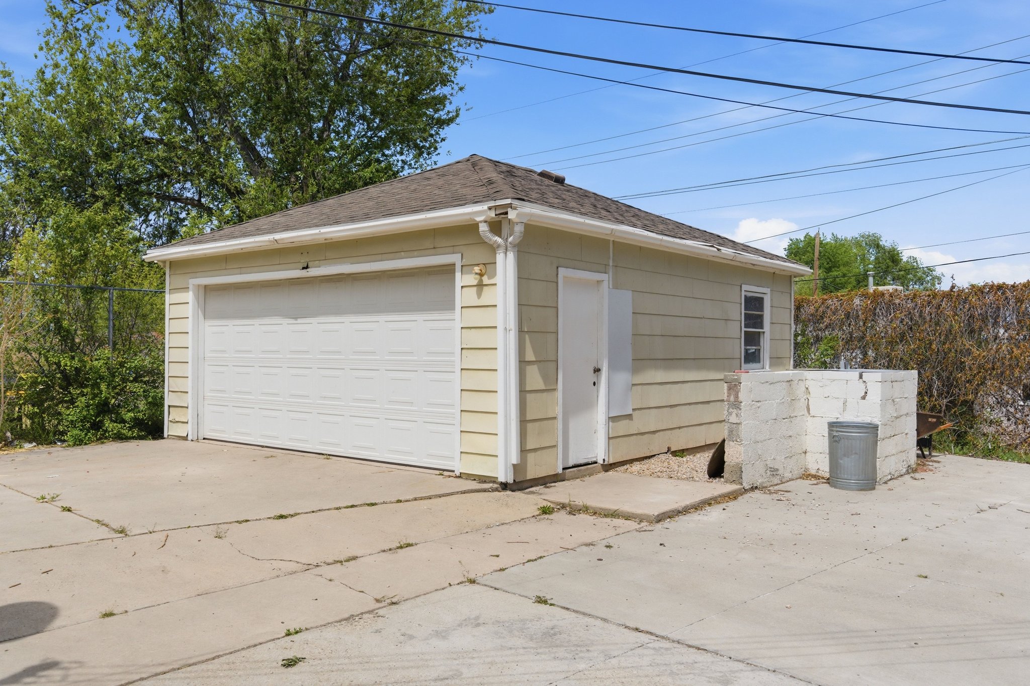 Detached garage featuring panel siding, a single overhead door, and a side access door