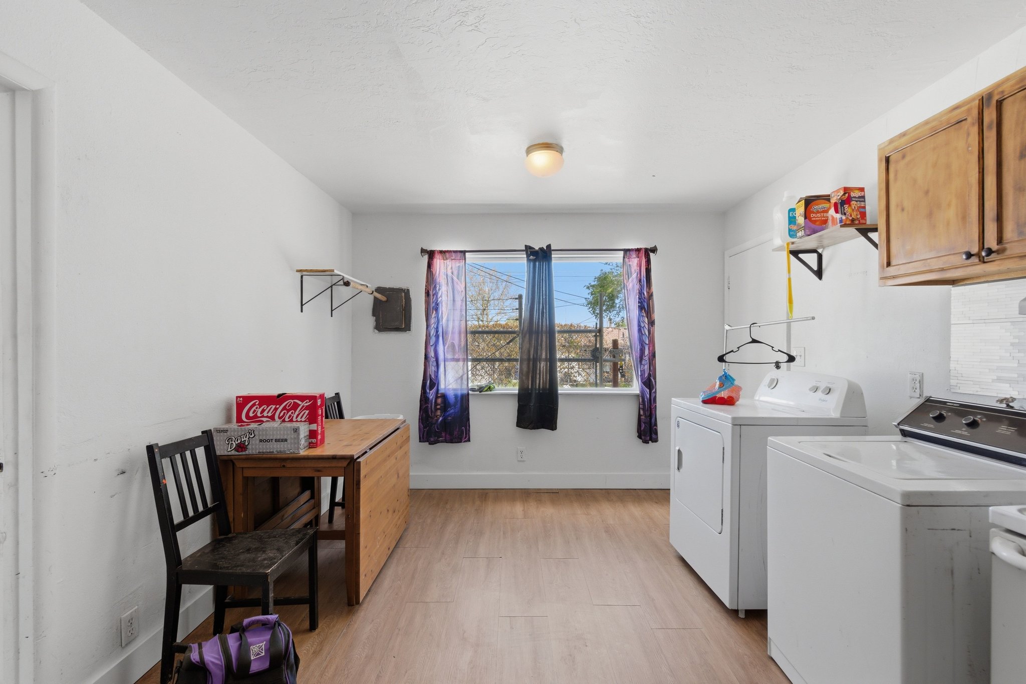 Utility room featuring wood-finish flooring, white walls, and a window with natural light