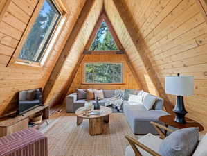 Living room with a wood ceiling with exposed beams and wooden walls