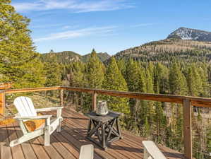 Wooden deck featuring a forest view and a mountain view