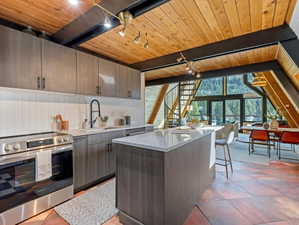 Kitchen with electric range, a center island, a wood ceiling with exposed beams, light stone counters, and modern cabinets
