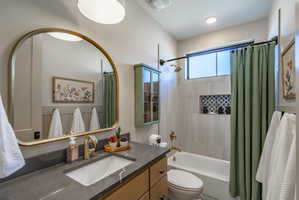 Bathroom featuring a vanity with an integrated sink, a dark countertop, and gold-toned hardware