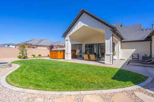 Expansive backyard featuring a curved lawn, a fire pit with stone surround, and a covered patio area