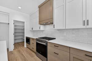 Modern kitchen featuring wood-finish flooring, white countertops, and a white subway tile backsplash
