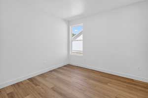 Room with wood-finish flooring, white baseboards, and a single window
