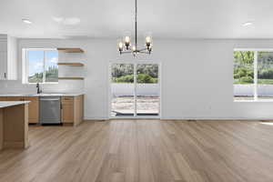 Open-concept living area featuring wood-finish flooring, a contemporary chandelier, and a sliding glass door providing access to the exterior