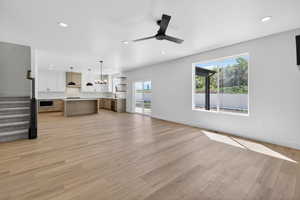 Open-concept living space featuring wood-finish flooring, recessed lighting, and a modern kitchen