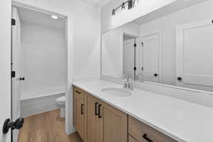 Bathroom featuring a wood-finish vanity with black hardware, a light-toned countertop, and an integrated sink with a chrome faucet