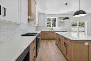 Contemporary kitchen featuring two-tone cabinetry with white upper and light wood-finish lower cabinets, quartz countertops, and a white subway tile backsplash