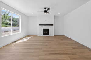Spacious room featuring wood-finish flooring, a contemporary fireplace with a tile surround and dark wood mantel, and large windows