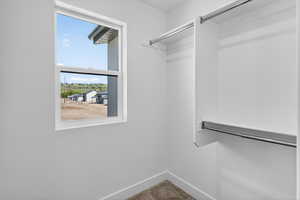 Well-lit closet space featuring a double-hung window, white walls, and built-in shelving with chrome hanging rods