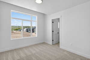 Room featuring light gray walls, plush carpet flooring, and a large multi-pane window