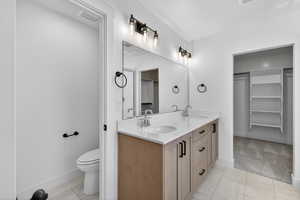Double vanity with light wood-finish cabinetry, white countertop, and contemporary black fixtures