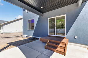 Covered patio with a composite deck, three-step staircase, and sliding glass door entry, featuring a recessed ceiling light