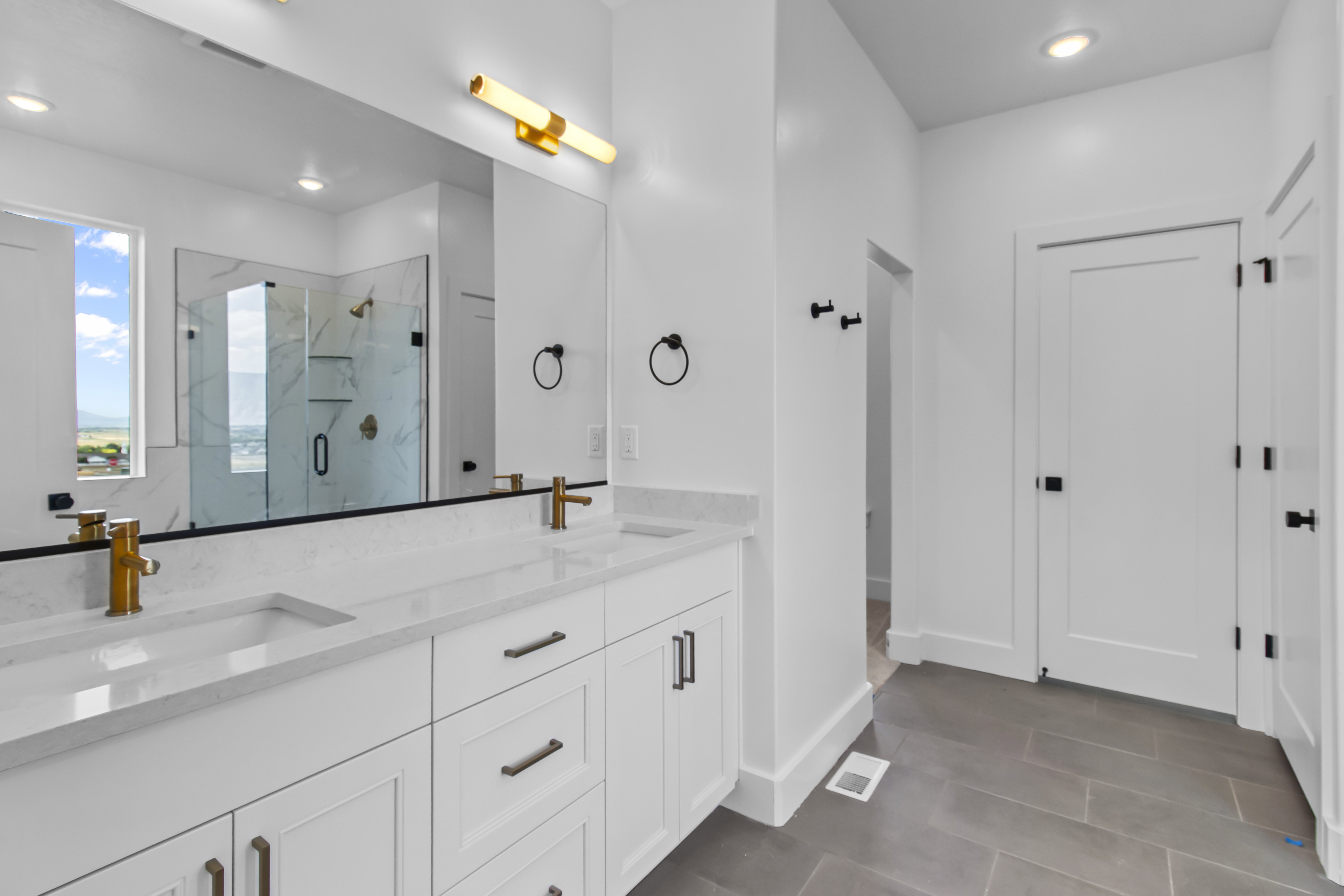 Modern bathroom featuring a dual vanity with white cabinetry and light-toned countertops