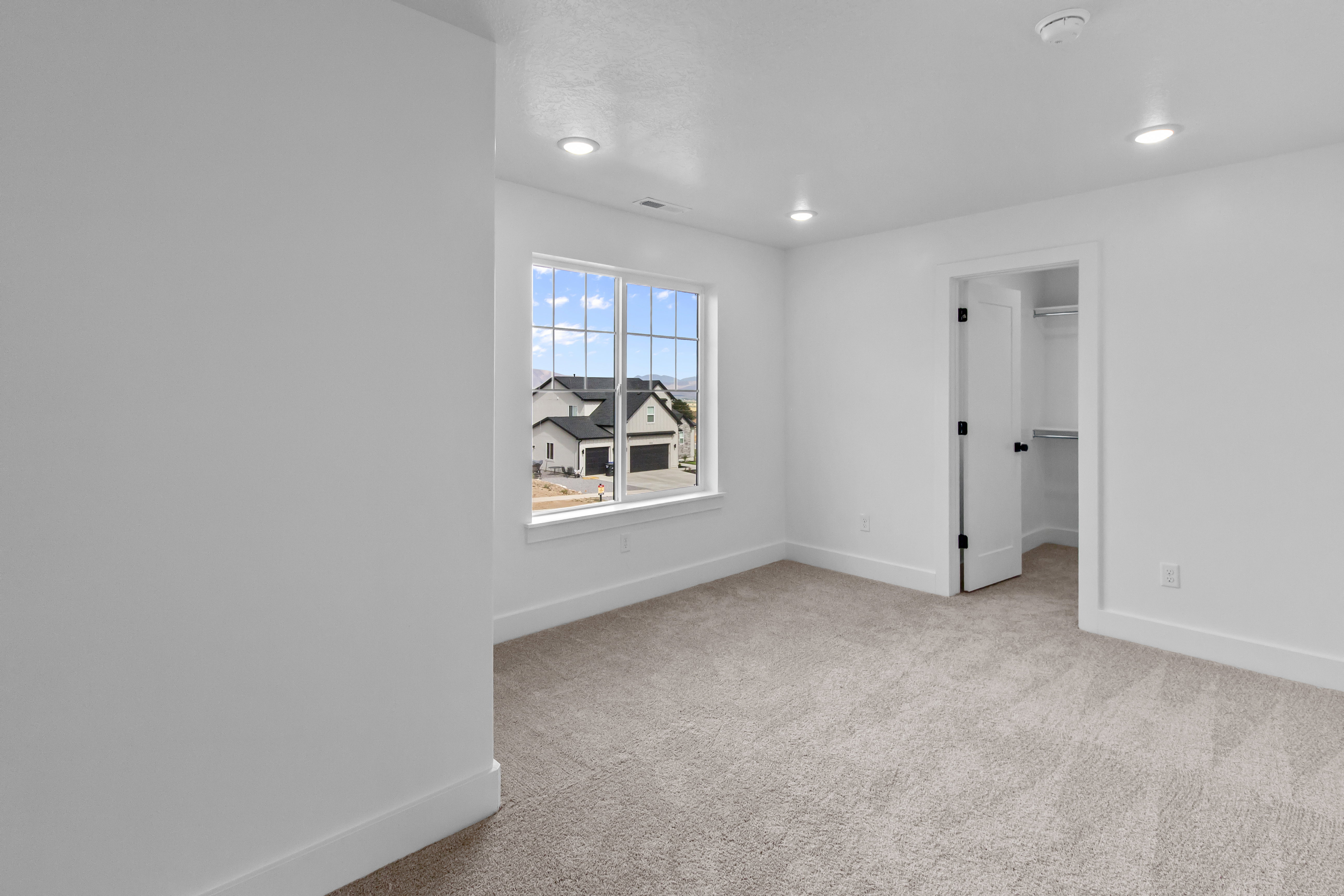 Room featuring a large window, neutral carpeting, recessed lighting, and a closet with an open door