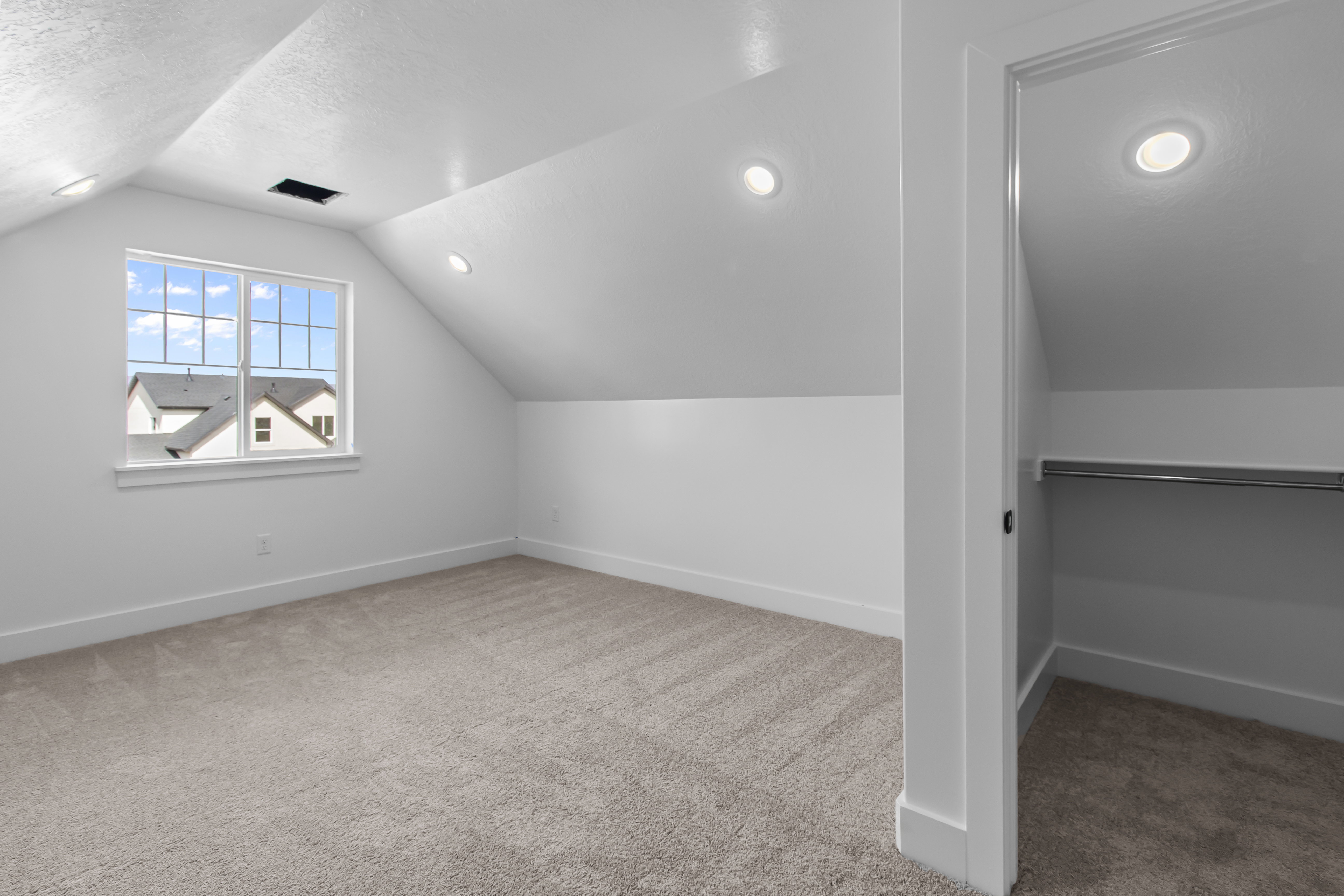 Attic room featuring neutral carpeting, a double-hung window, recessed lighting, and a closet with a hanging rod