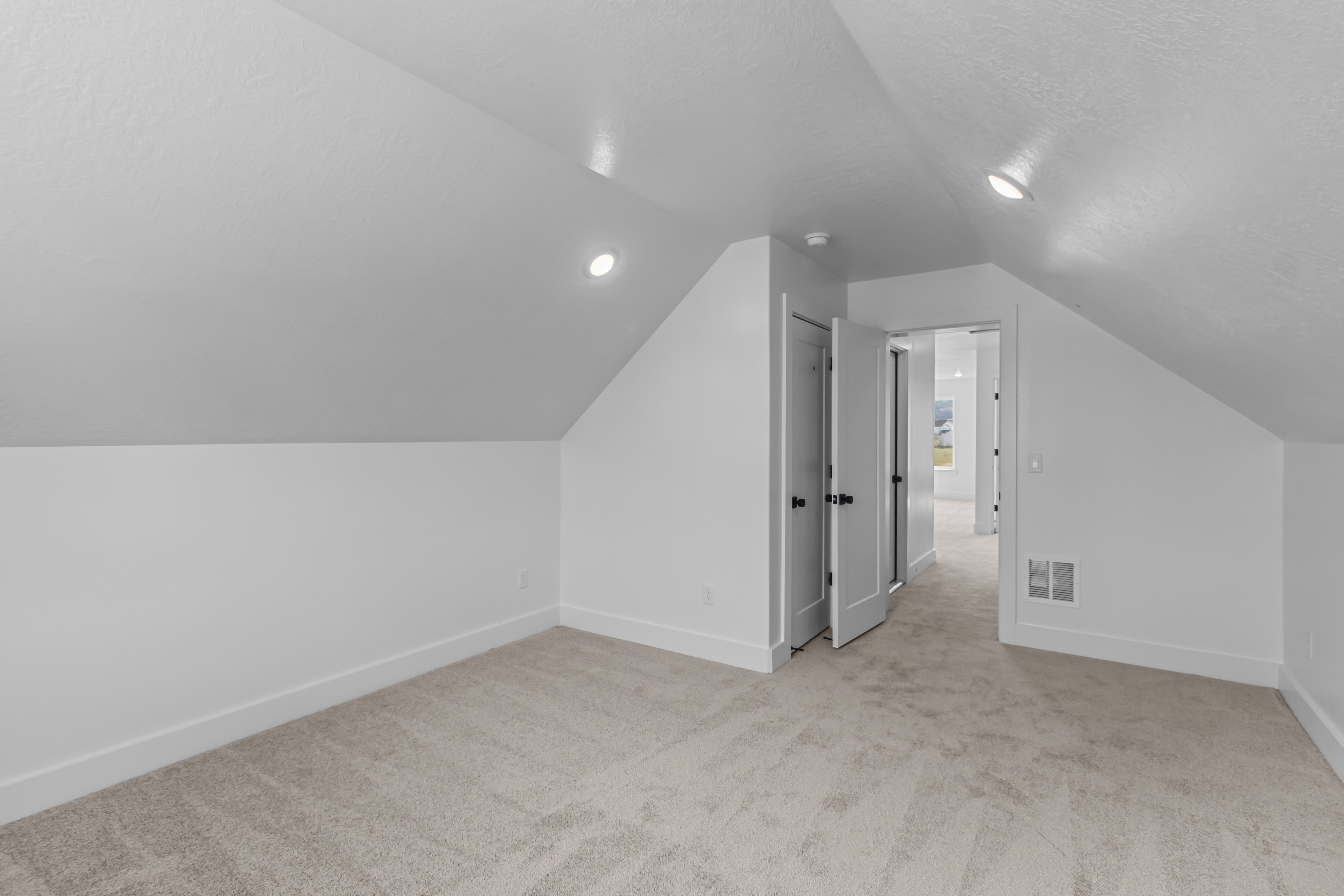 Carpeted attic space featuring sloped ceilings, recessed lighting, and white baseboards