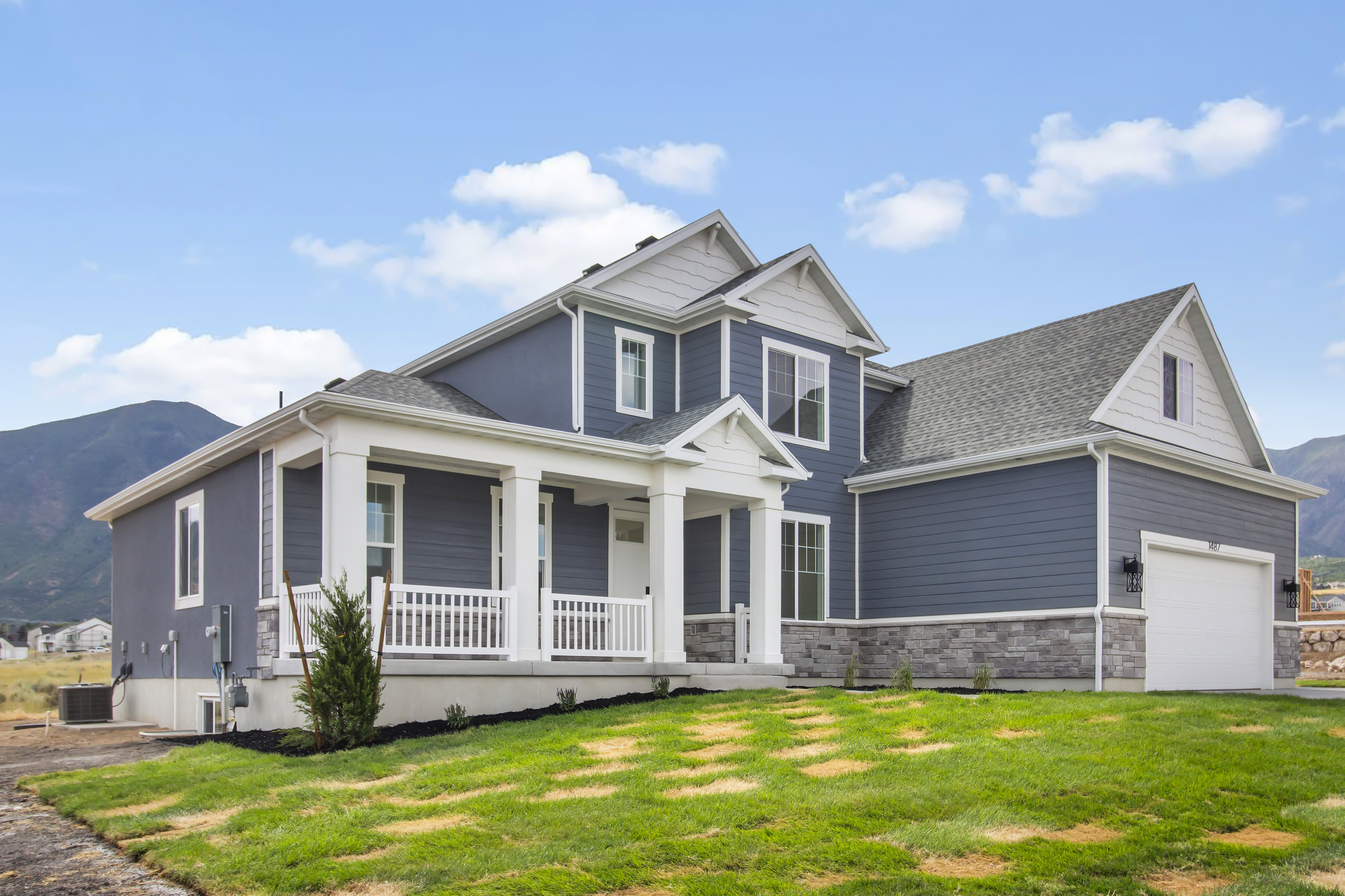 Contemporary home exterior featuring blue siding, white trim, and a prominent covered porch with white railings