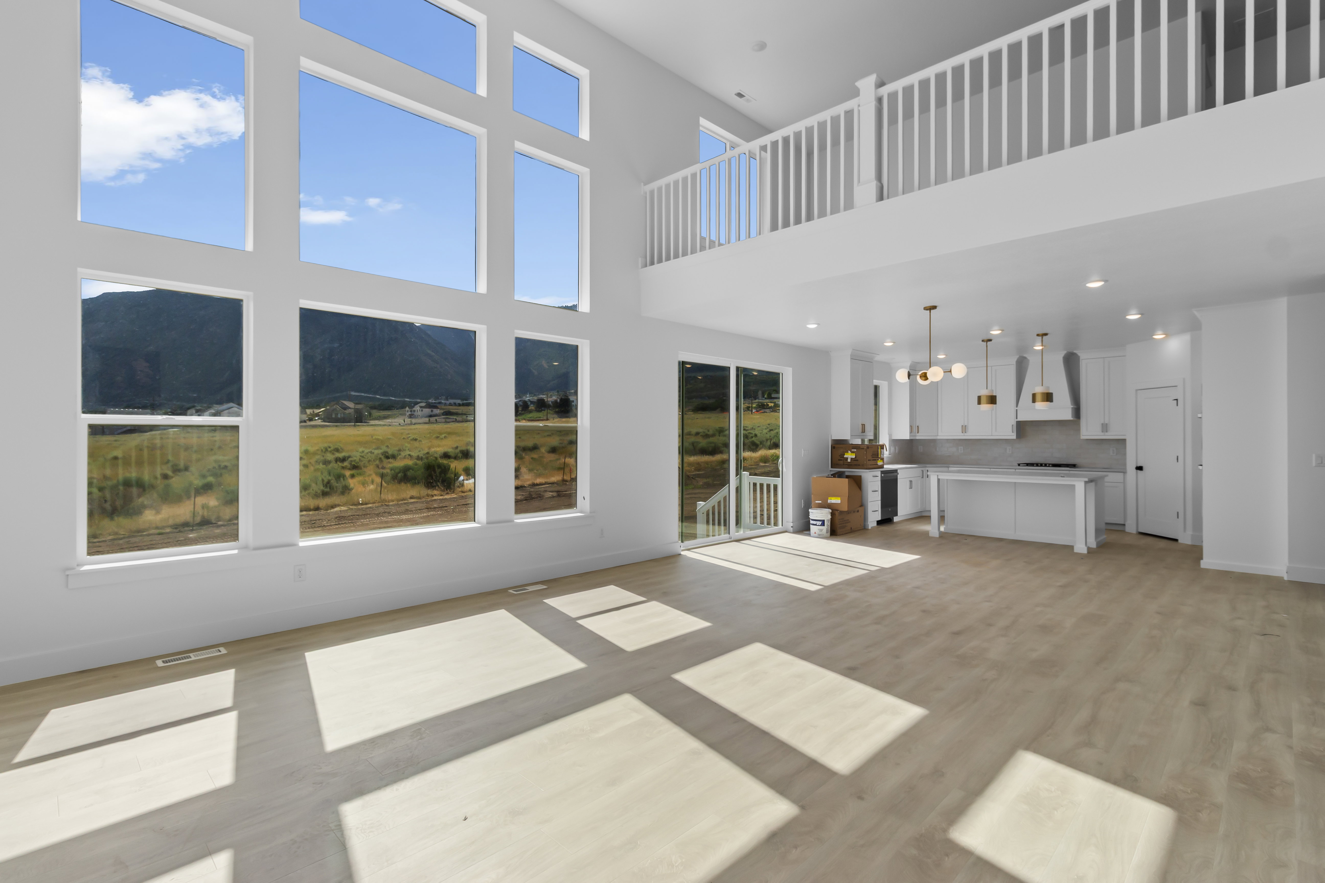 Two-story living area with expansive window wall, light wood-finish flooring, and a sliding glass door