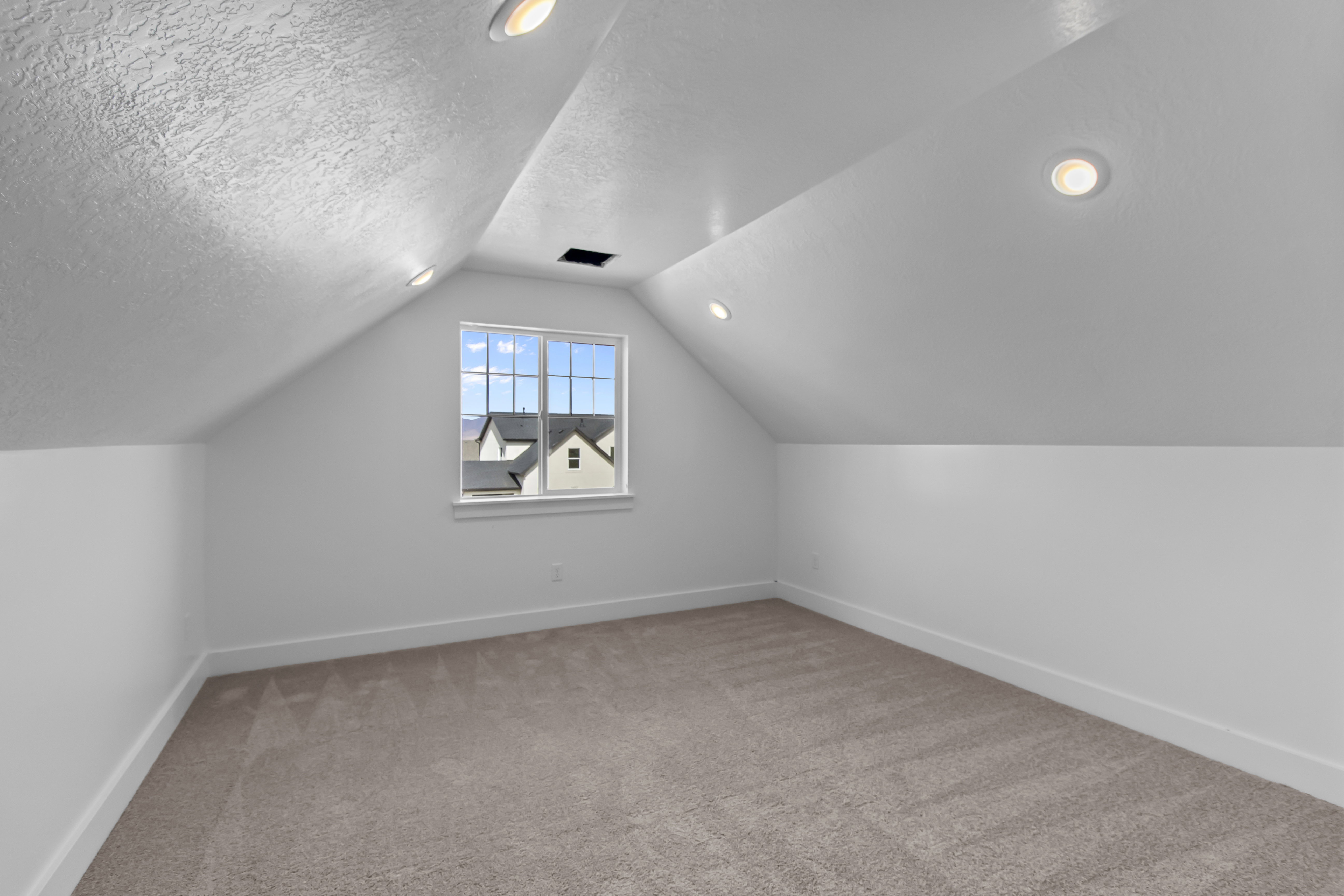 Carpeted room with sloped ceilings and recessed lighting