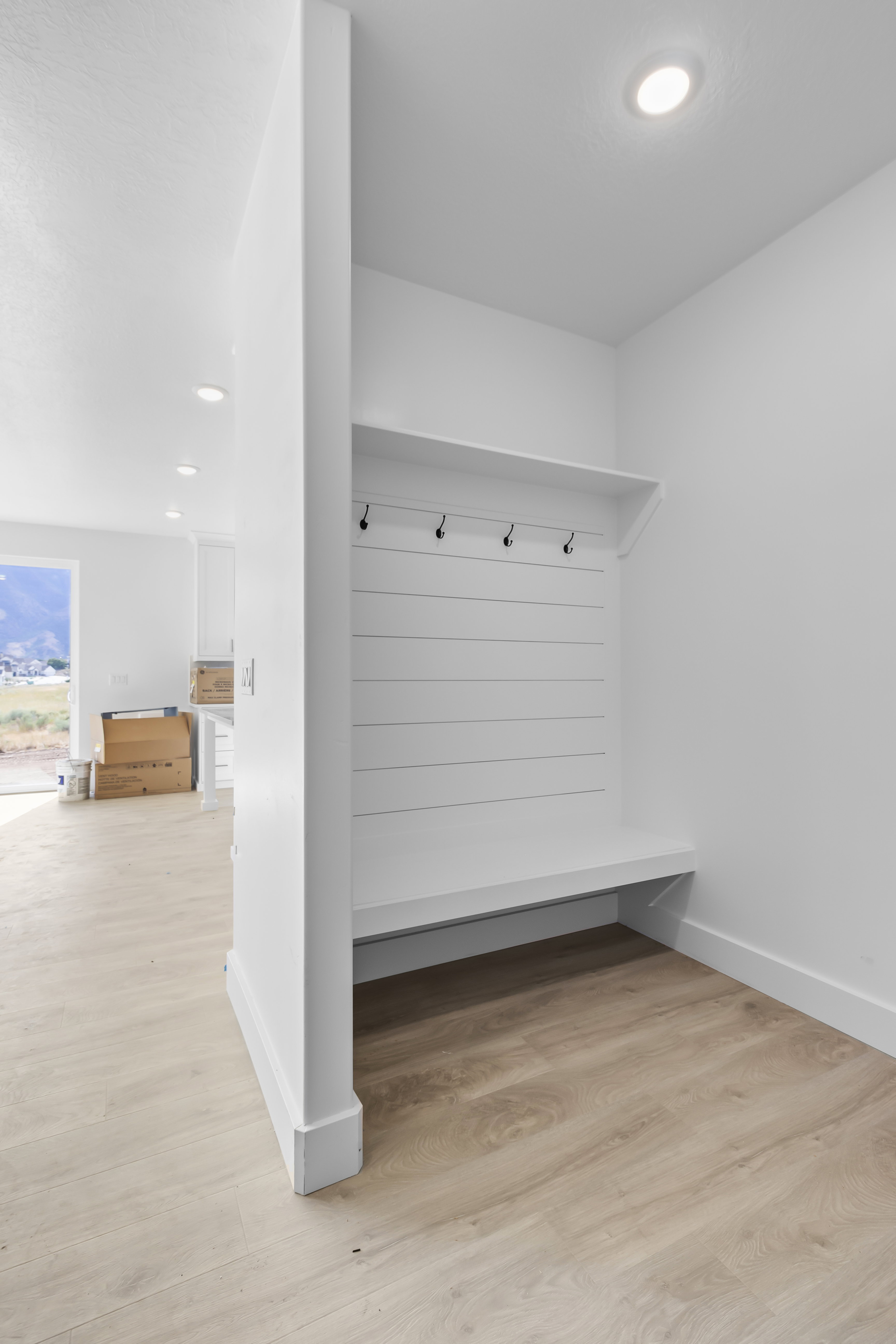 Built-in mudroom bench with shiplap backing, storage shelf, and four coat hooks