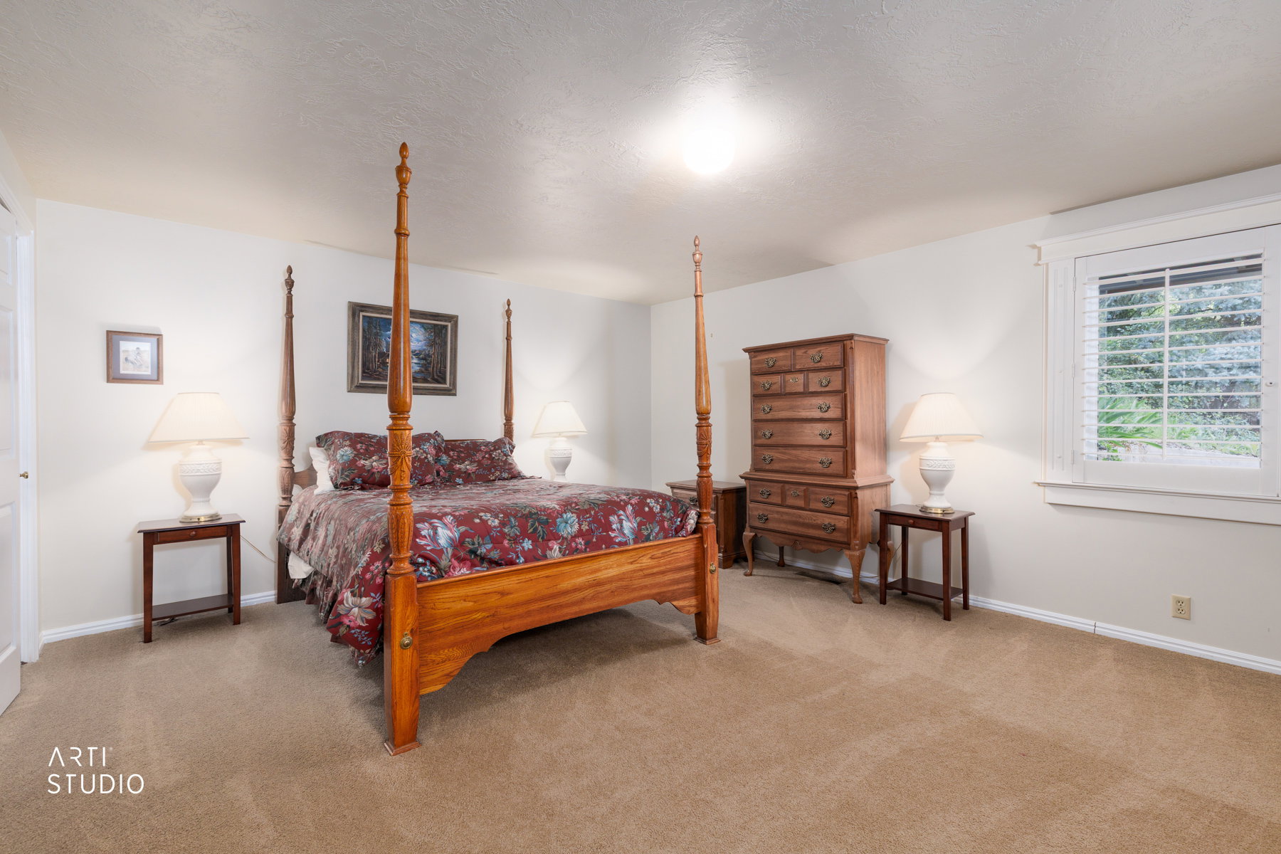 Spacious room featuring neutral carpeting, light-toned walls, and a window with plantation shutters