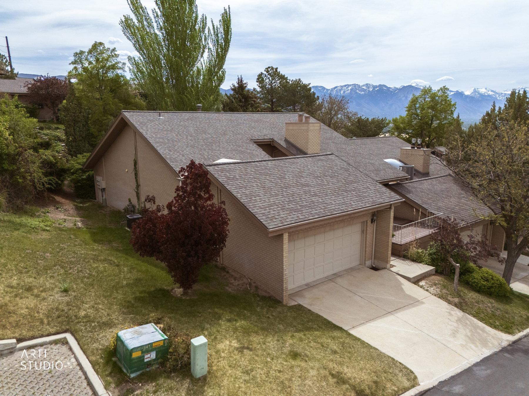 Northwest corner of residence featuring a two-car garage, brick exterior, and a shingled roof