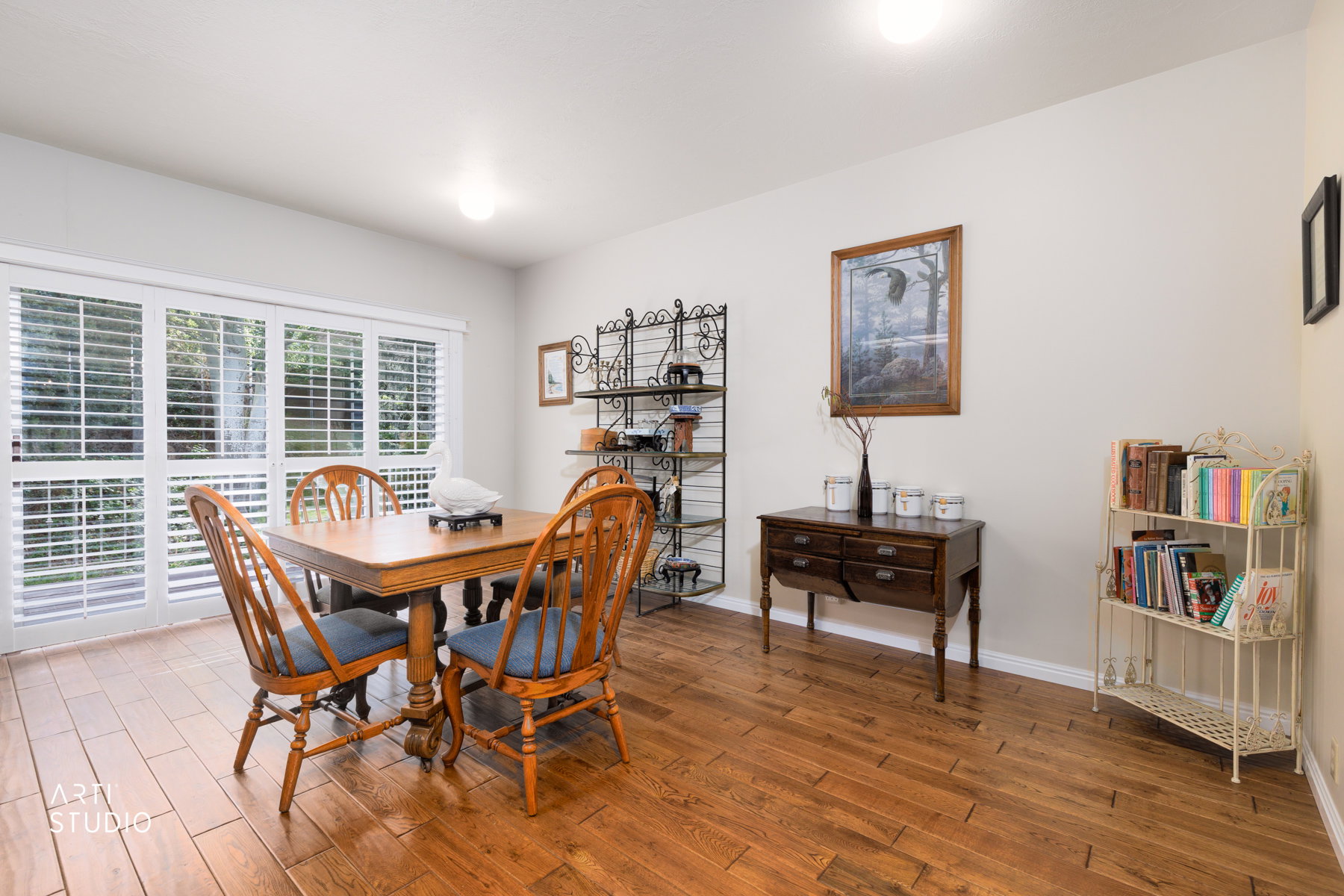 Interior space featuring rich wood-finish flooring, white walls, and a large multi-pane window with white plantation shutters