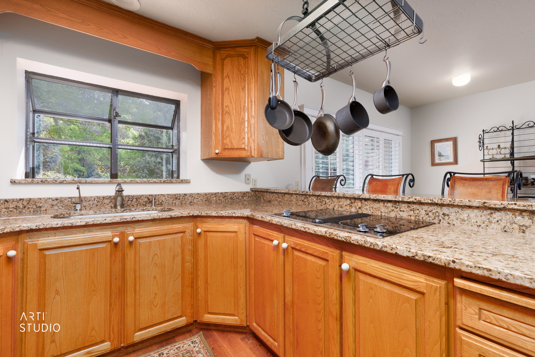 Kitchen featuring wood cabinetry, light-toned speckled countertops, a built-in cooktop, and a stainless steel sink with a single-handle faucet