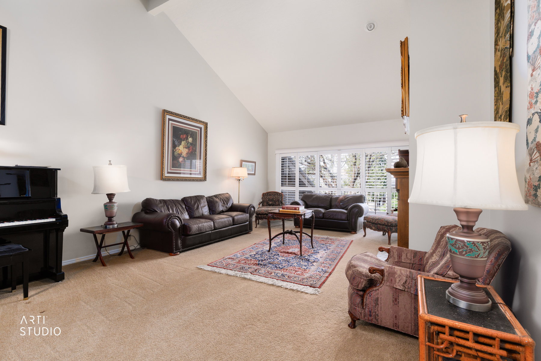 Spacious living area featuring a vaulted ceiling and light beige carpet