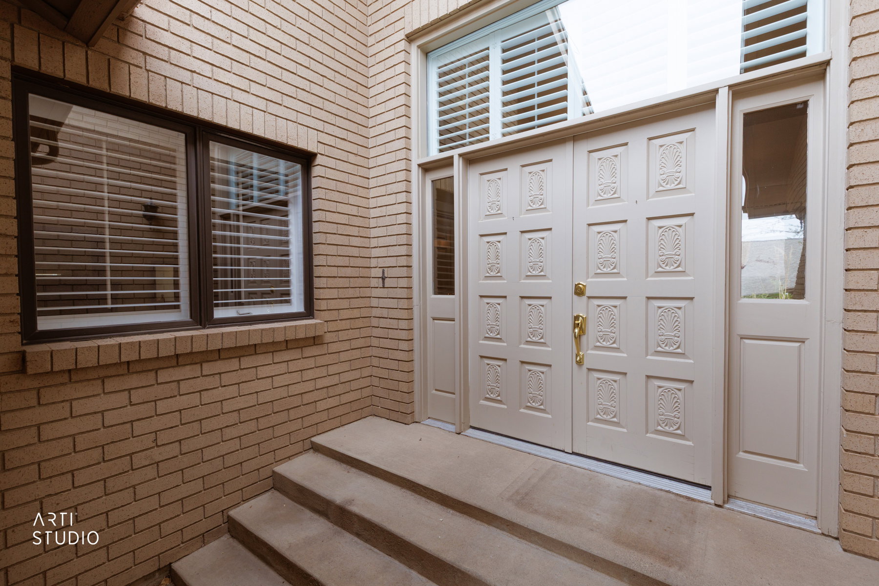 Entryway featuring a double door with decorative panels, sidelights, and a transom window with plantation shutters