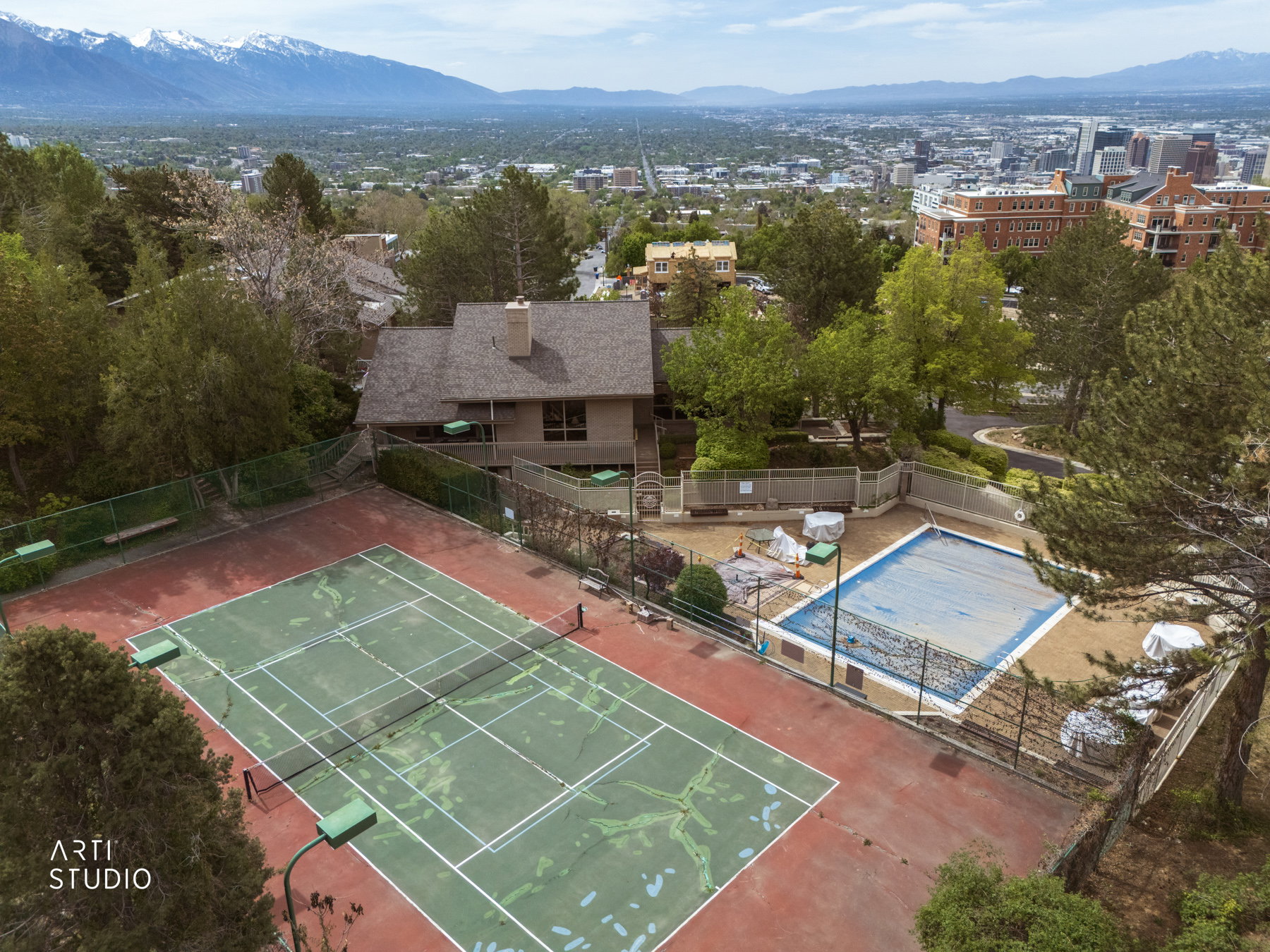 Aerial view of clubhouse area showing tennis court and covered pool