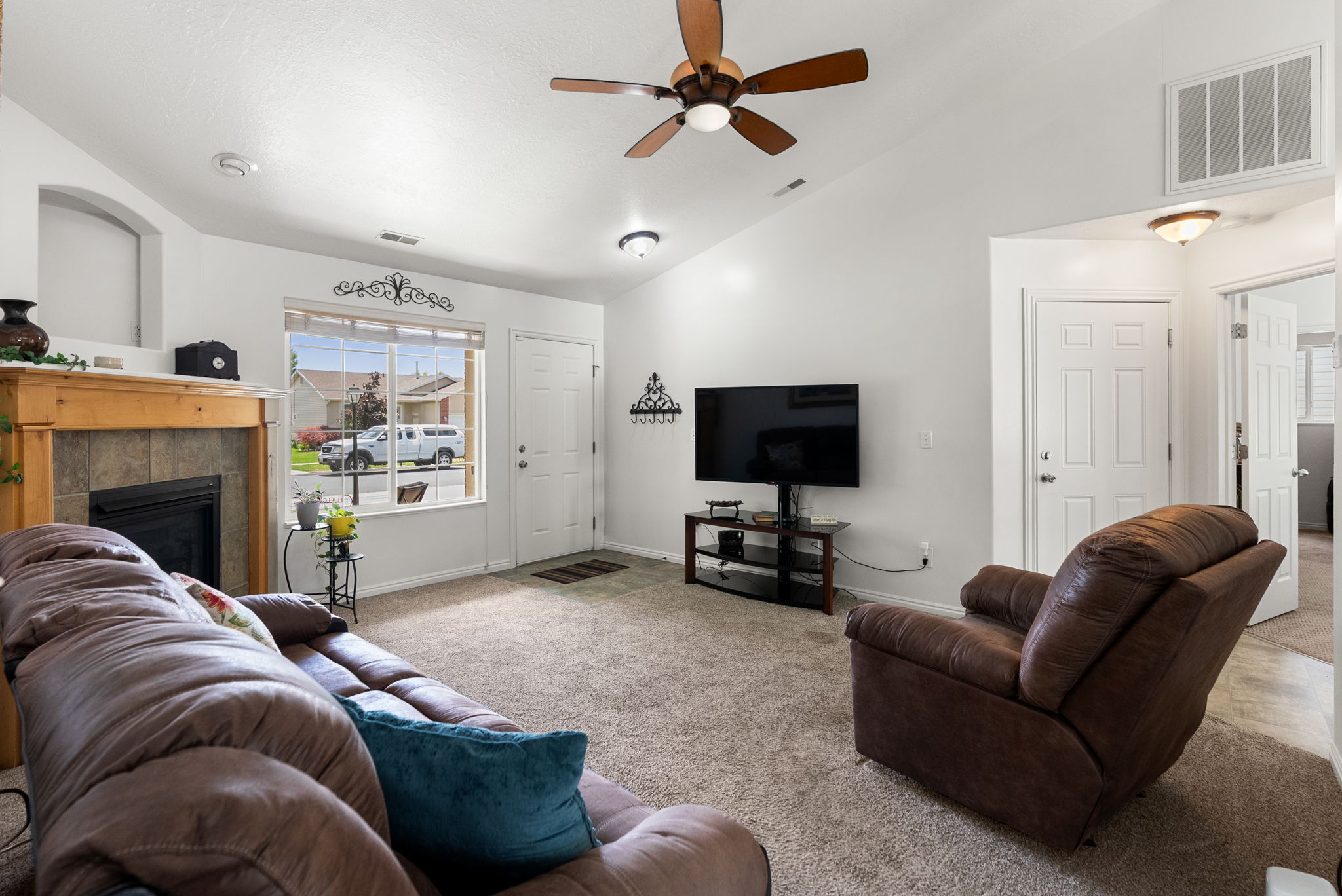 Carpeted living area featuring a vaulted ceiling and a ceiling fan with light fixture
