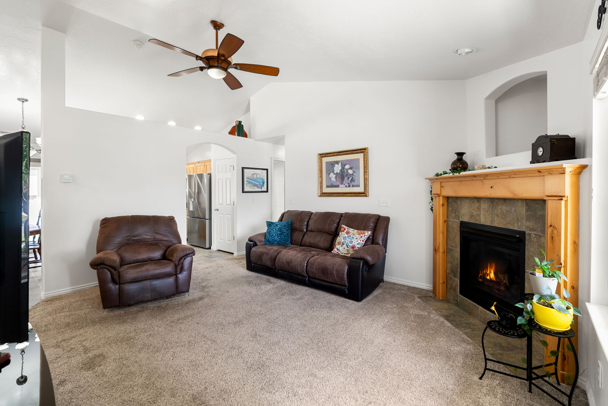 Living area featuring vaulted ceilings, recessed lighting, a ceiling fan with light fixture, and a fireplace with a wood mantel and tile surround