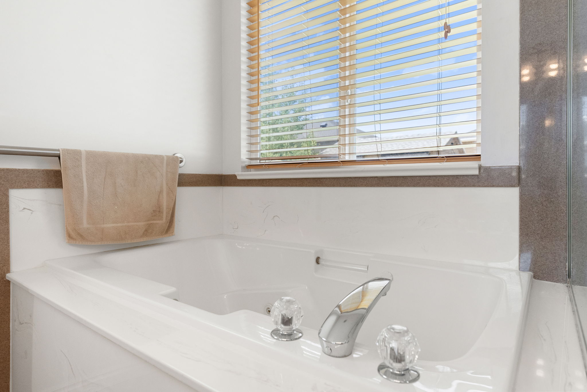 Soaking tub with a polished chrome faucet and crystal-style handles, set against a tiled surround