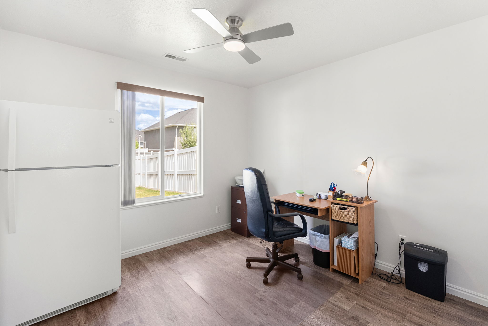 Bright room featuring wood-finish flooring and a ceiling fan with integrated lighting