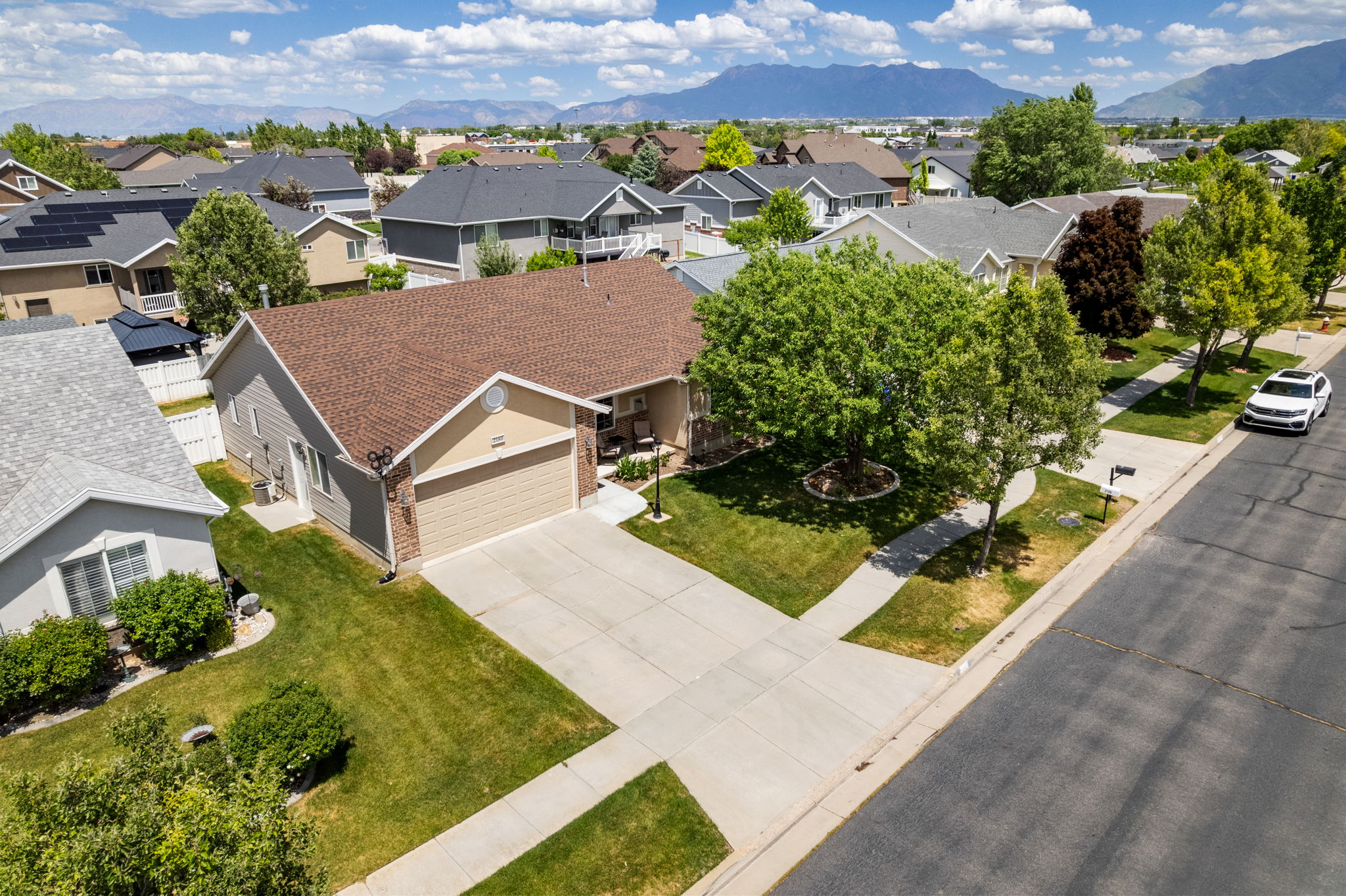 Single-story residence featuring a two-car garage, concrete driveway, and a tan and gray exterior