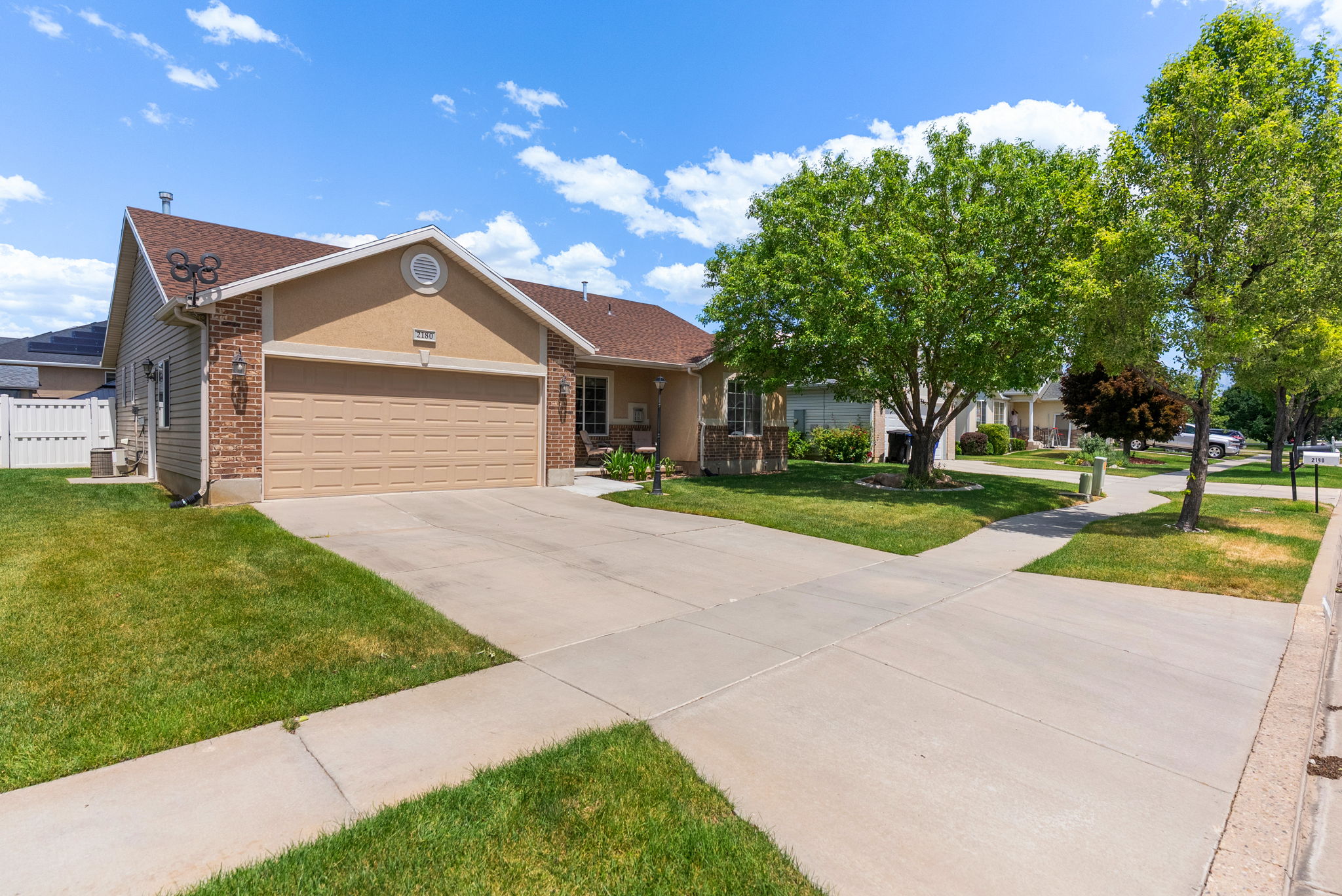 Single-story residence featuring a two-car garage with a paneled door, partial brick veneer, stucco siding, and a gabled roof