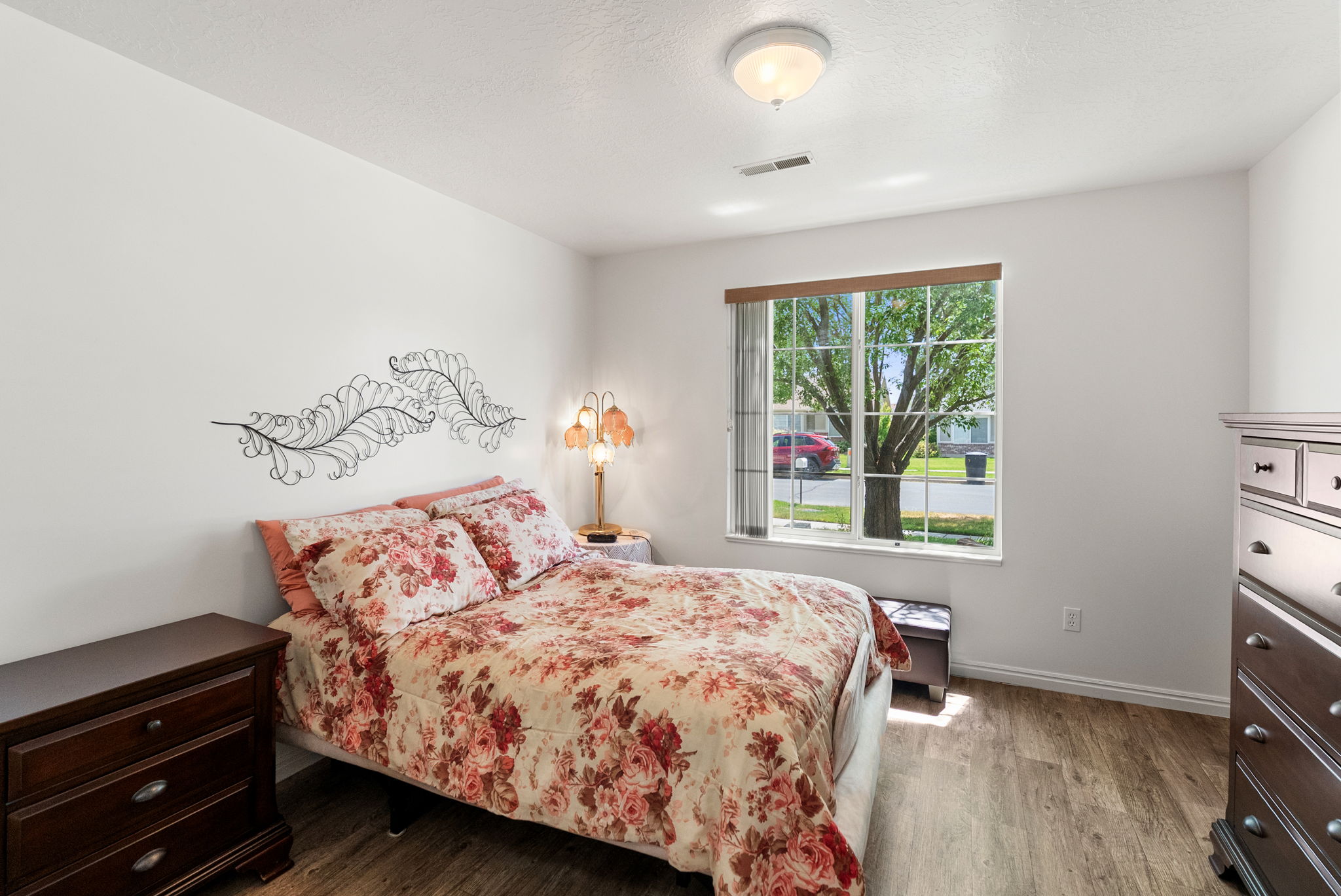 Bedroom with wood-finish flooring, a window offering exterior views, and a flush-mount ceiling light fixture