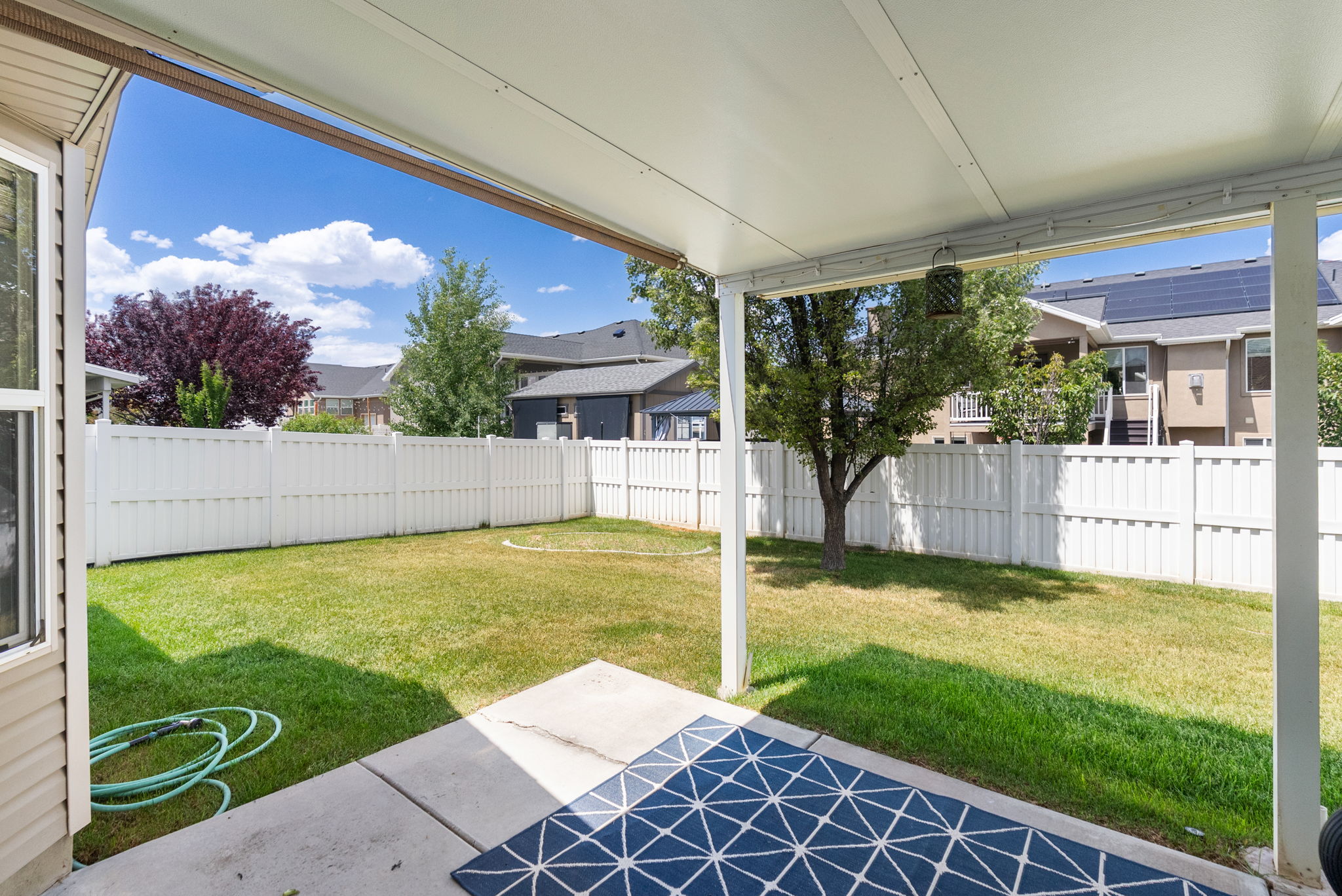 Covered patio featuring a concrete slab and a fully fenced backyard with mature trees