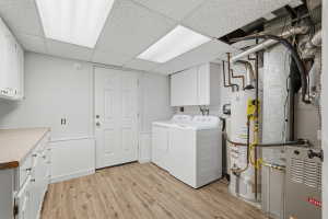 Laundry area featuring wood-finish flooring, white cabinetry, and recessed lighting