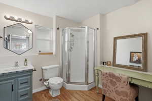 Bathroom featuring a corner shower enclosure, wood-finish flooring, and a window with a sill