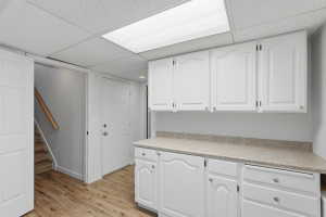 Utility area featuring wood-finish flooring and a drop ceiling with integrated lighting