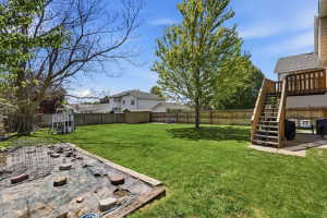 Expansive backyard featuring a manicured lawn, a raised garden bed, and a privacy fence