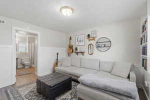Living area featuring light wall tones, lower wall paneling, and wood-finish flooring
