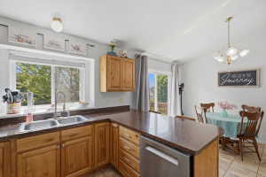 Kitchen featuring wood cabinetry, a double basin stainless steel sink, a stainless steel dishwasher, and ample counter space