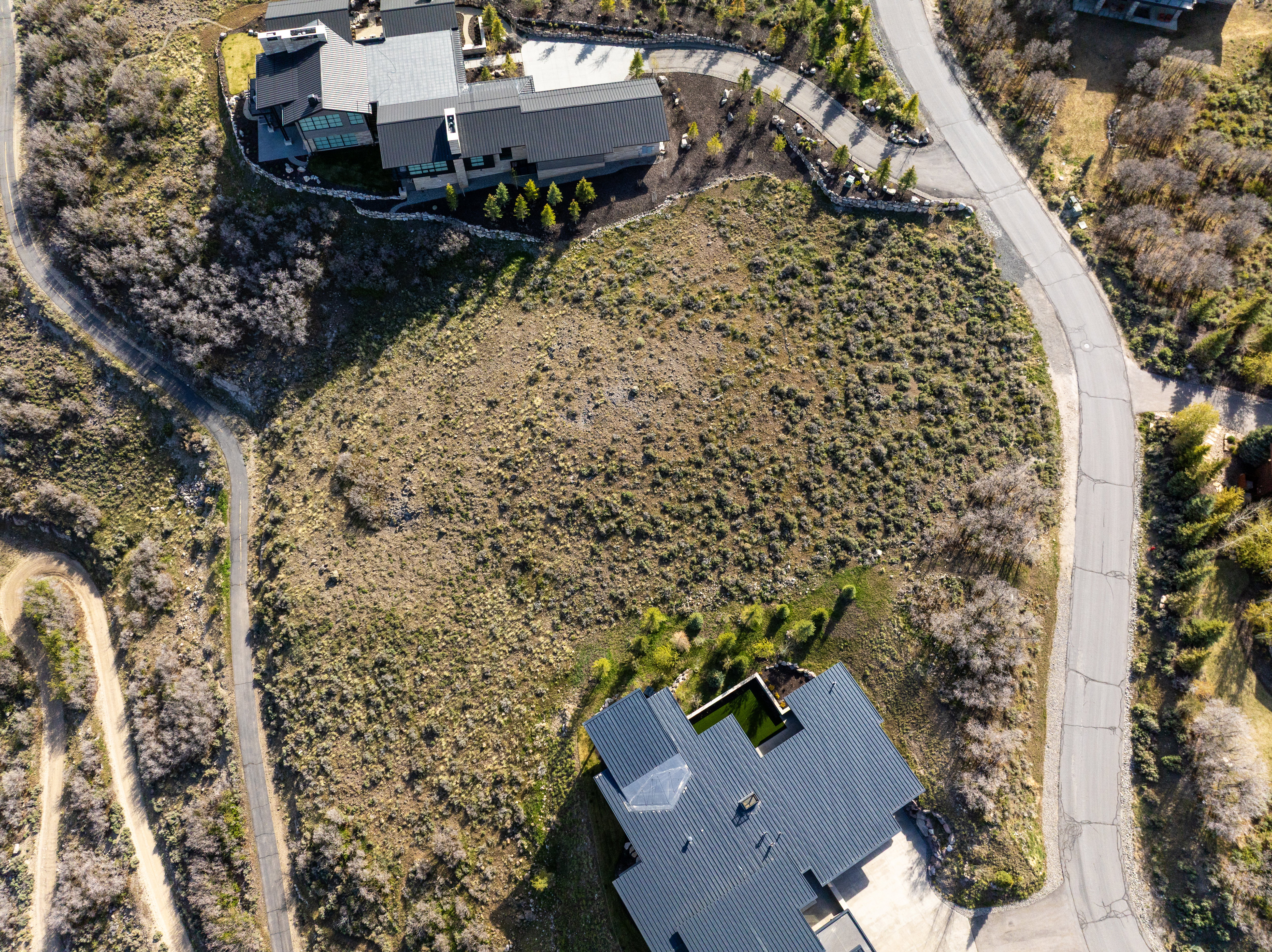 Expansive vacant lot featuring natural vegetation and surrounding paved roads
