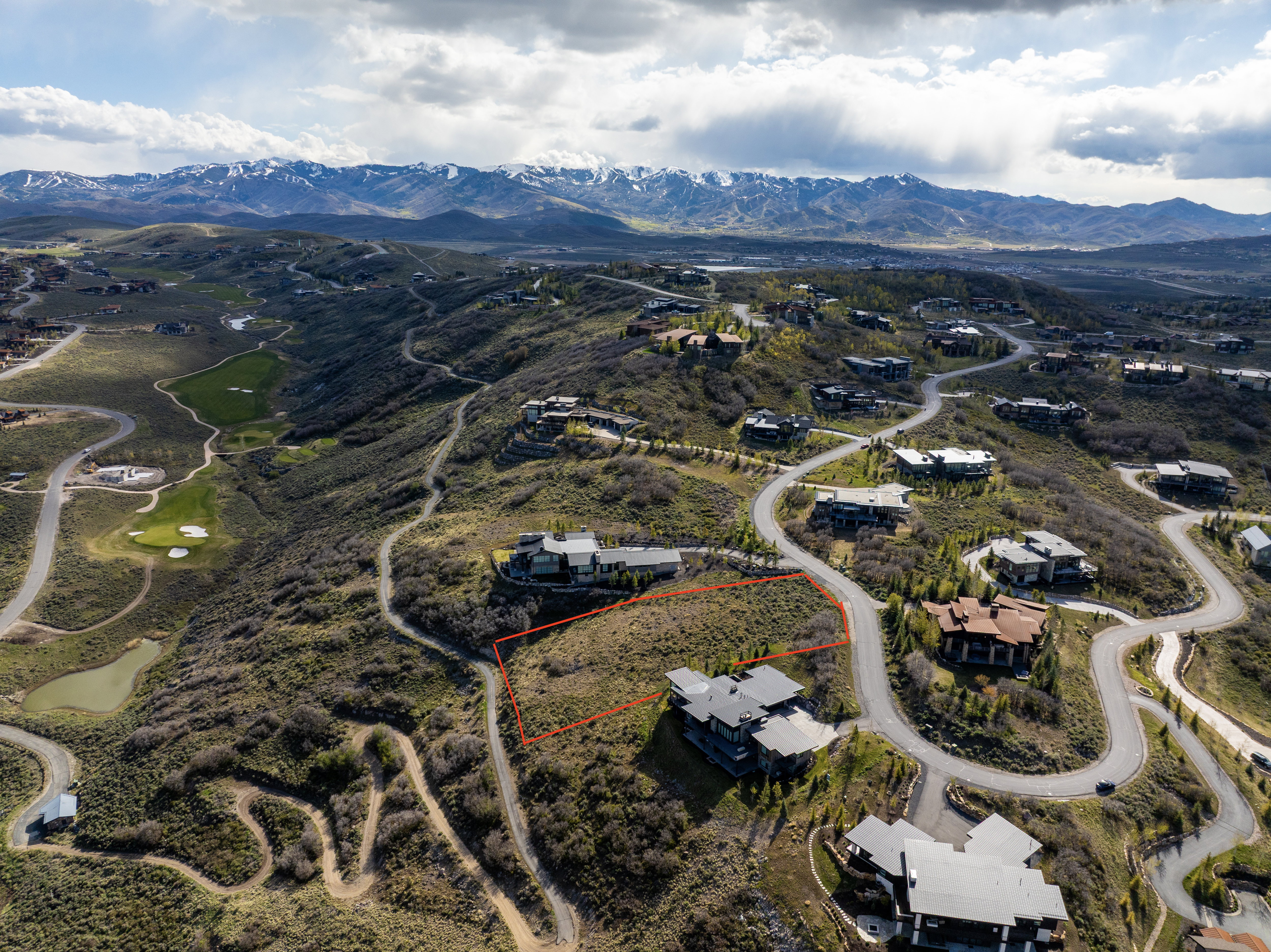 Expansive hillside building lot featuring a natural, undeveloped landscape and a winding paved road access
