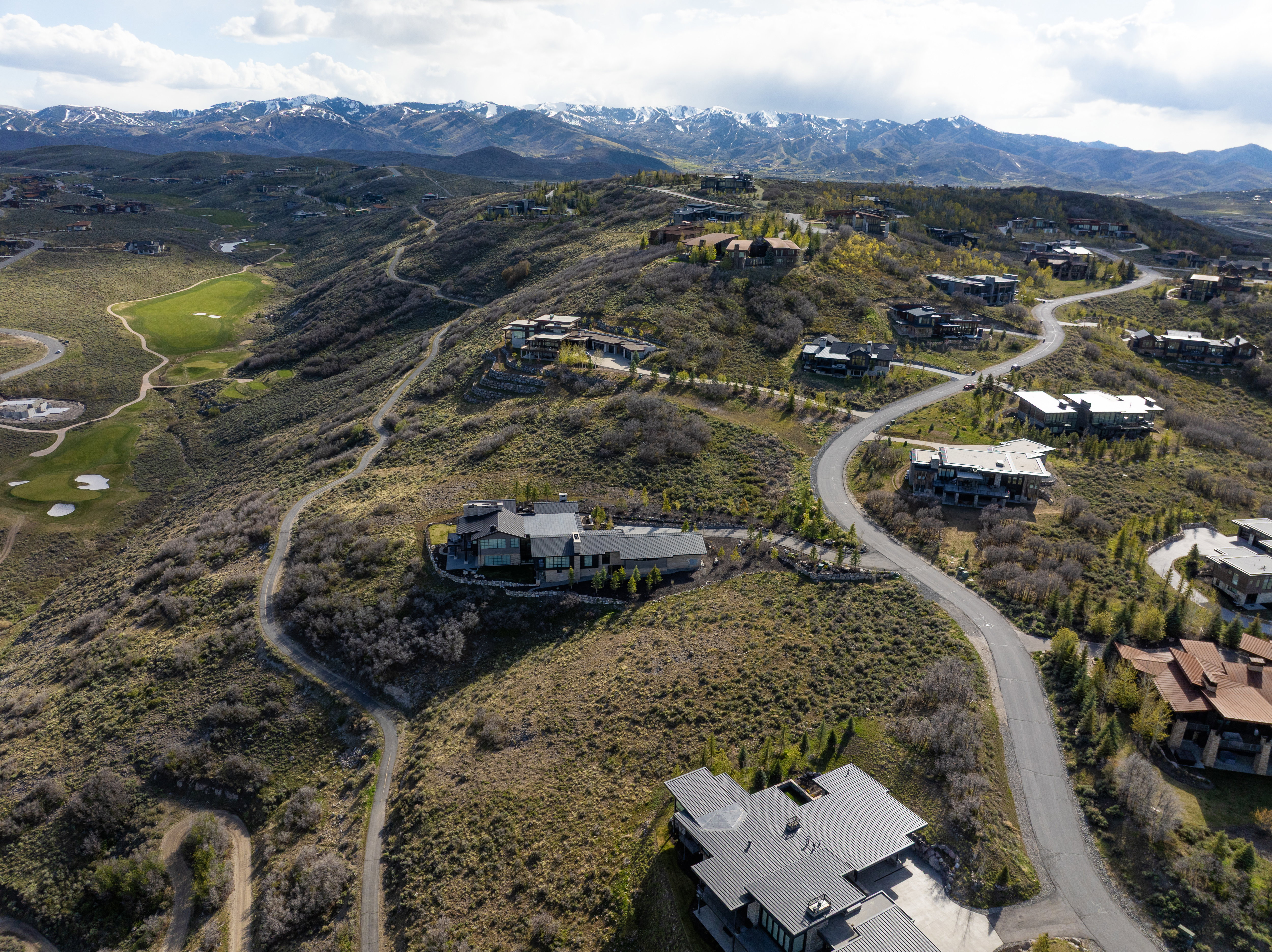 Modern residential property situated on a sloped lot, featuring multiple levels and dark exterior finishes